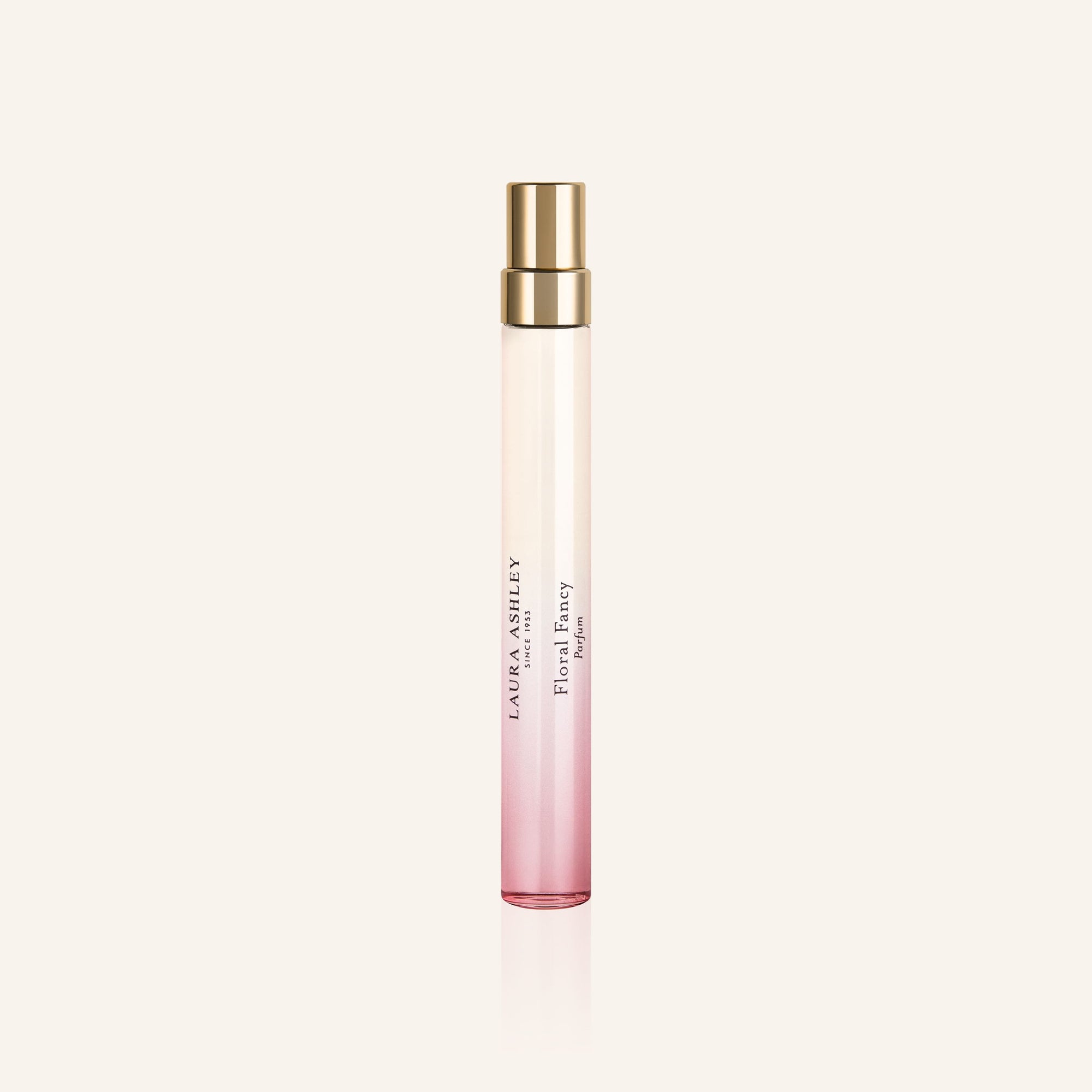 Laura Ashley Floral Fancy Perfume bottle with pink gradient and gold cap on a light beige background